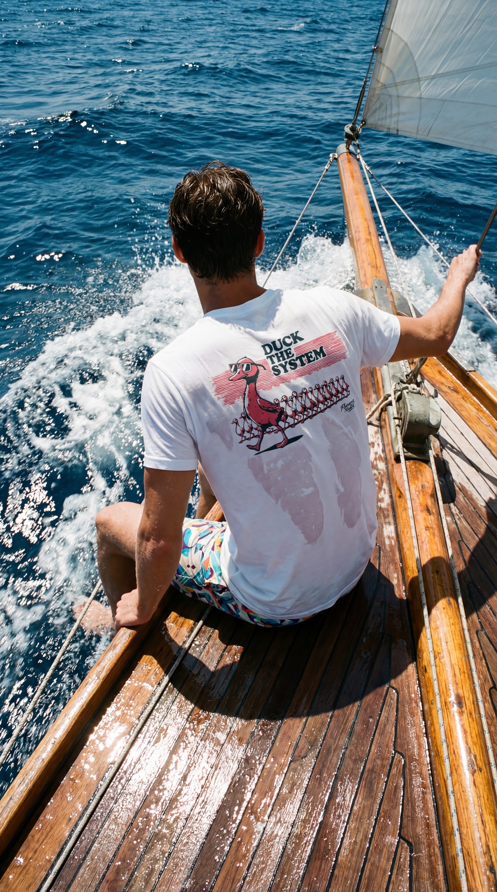 A bordo de un velero de madera clásico con camiseta gráfica Flamenco Maltés